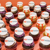 Halloween Corporate Cupcakes with Logos from Crumbs & Doilies featuring edible sugarpaste YouTube logos on various flavored cupcakes.